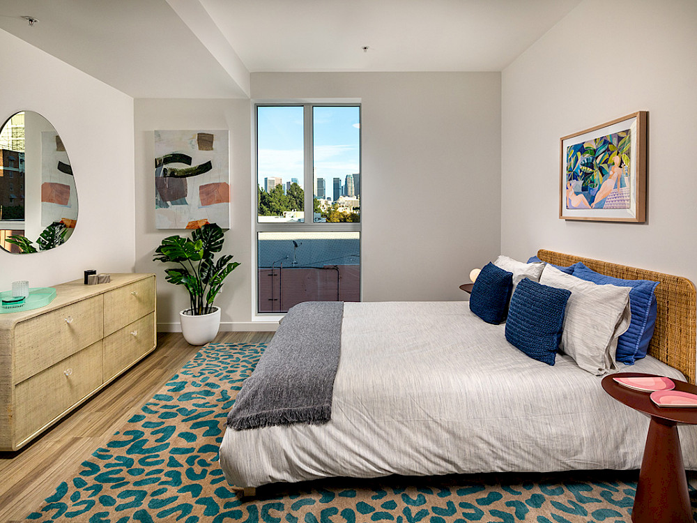 Wilco Apartments in Westlake - Master Bedroom with Stylish Decor, Wood-Style Plank Flooring, White Walls, and Large Window
